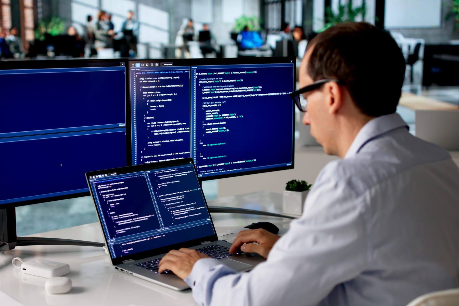 Software developer at a workstation with multiple screens